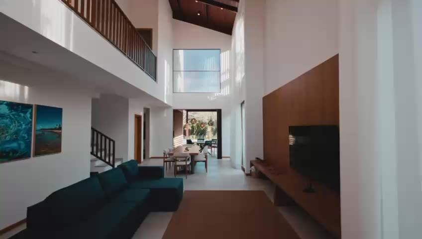 Salón de doble altura con escalera volada y el comedor al fondo, recorrido en un plano continuo.